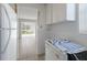 Kitchen leading to sunroom, featuring white appliances and cabinets, and neutral tile flooring at 5400 Gulf Dr # 25, Holmes Beach, FL 34217