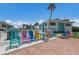 Community pool area features colorful Adirondack chairs, a palm tree and a partial view of a modern two story building at 5400 Gulf Dr # 25, Holmes Beach, FL 34217
