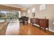 Bright living area with piano, view of pool, and hardwood floors at 6547 Oakland Hills Dr, Lakewood Ranch, FL 34202