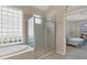 Sunlit main bathroom with a glass block window, soaking tub, walk-in shower and entrance to the main bedroom at 6547 Oakland Hills Dr, Lakewood Ranch, FL 34202