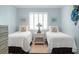Serene bedroom features twin beds, a decorative lamp, and charming beach-themed wall art at 6700 Gulf Dr # B8, Holmes Beach, FL 34217