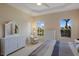 A well-lit main bedroom features a comfortable chair, dresser and backyard view at 7017 Lennox Pl, University Park, FL 34201