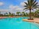 A luxurious community pool is surrounded by palm trees and lounge chairs at 8403 Grand Estuary Trl # 103, Bradenton, FL 34212