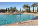 A large community pool with lounge seating, palm trees, and brick pavers at 8403 Grand Estuary Trl # 103, Bradenton, FL 34212