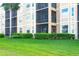 Exterior view of an apartment balcony featuring a screened-in porch and lush green landscaping around the building at 8403 Grand Estuary Trl # 103, Bradenton, FL 34212
