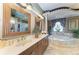 Primary bath features a double sink vanity, decorative mirrors, tile floors, and a soaking tub at 10002 Cherry Hills Avenue Cir, Bradenton, FL 34202