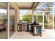 Enclosed patio with an outdoor kitchen featuring a grill and custom-built wooden cabinets at 10306 Palmbrooke Ter, Bradenton, FL 34202