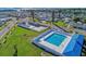 Aerial view of community pool, tennis courts, shuffle board, and neighborhood near the water at 10315 Cortez W Rd # 17F, Bradenton, FL 34210