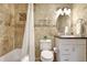 Bathroom with stone tile, shower-tub combo, and a round decorative mirror at 1141 W Peppertree Dr # 1141, Sarasota, FL 34242