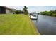 Waterfront backyard with lush grass lawn, boat dock, and canal access at 15484 Alsask Cir, Port Charlotte, FL 33981