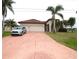 Front exterior of home featuring a large driveway, three car garage, and beautiful landscaping at 15484 Alsask Cir, Port Charlotte, FL 33981