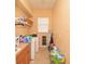 Bright laundry room featuring tile floors, overhead shelving, and a window for natural light at 15484 Alsask Cir, Port Charlotte, FL 33981