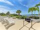 Community outdoor pool deck with lounge chairs, tables, and grill overlooking the waterfront at 1618 Stickney Point Rd # 101, Sarasota, FL 34231