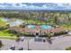 Aerial view of a luxurious community pool area, showcasing palm trees, ample lounge chairs, and a clubhouse at 17739 Cantarina Cv, Bradenton, FL 34211