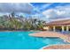 A luxurious community pool with ample seating, palm trees, and a beautiful building, perfect for relaxation at 17739 Cantarina Cv, Bradenton, FL 34211