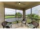 Screened balcony featuring wicker chairs and a scenic view of the lake and palm trees at 18008 Gawthrop Dr # 308, Bradenton, FL 34211
