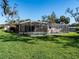 Backyard view featuring a lush green lawn and a screened-in swimming pool enclosure at 1838 Sandalwood Dr, Sarasota, FL 34231