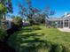 Expansive backyard featuring a lush lawn, mature trees, and a screened pool enclosure at 1838 Sandalwood Dr, Sarasota, FL 34231