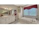 Elegant bathroom with double vanities, a soaking tub with marble surround, and great natural light at 20 Bayhead Ln, Osprey, FL 34229