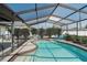 In-ground pool features a screened enclosure, safety fence, and a sun shelf with chairs at 2211 51St W St, Bradenton, FL 34209