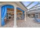 Covered outdoor patio with stone pillars, blue curtains, and furniture, overlooking the pool at 22642 Morning Glory Cir, Bradenton, FL 34202