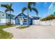Charming blue home with tropical landscaping features a welcoming front door and ample parking space at 2408 Avenue B, Bradenton Beach, FL 34217