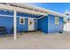 Charming blue home featuring a white door, outdoor shower, and stone walkway leading to a cozy outdoor seating area at 2408 Avenue B, Bradenton Beach, FL 34217