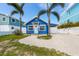 Charming blue home with tropical landscaping features a welcoming front door and ample parking space at 2408 Avenue B, Bradenton Beach, FL 34217