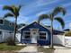 Adorable blue cottage featuring a well-manicured lawn, palm trees, and a welcoming front door at 2408 Avenue B, Bradenton Beach, FL 34217