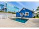 Backyard pool with nearby trees, patio furniture, and lush greenery with a blue house at 2408 Avenue B, Bradenton Beach, FL 34217