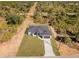 Aerial view of home with dark roof in an area with native trees; the lot is landscaped with a long drive at 302 Liden St, Port Charlotte, FL 33953