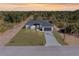 Aerial view of a modern home with gray roof, surrounded by lush greenery, and a paved driveway at 302 Liden St, Port Charlotte, FL 33953