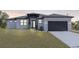 Contemporary home featuring a gray and white exterior, well-manicured lawn, and a sleek black garage door at 302 Liden St, Port Charlotte, FL 33953