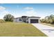 Contemporary home with a minimalist design, featuring a dark garage door and neatly trimmed front lawn at 302 Liden St, Port Charlotte, FL 33953