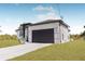Side view of the home showcasing the dark garage door, white siding, and neatly trimmed lawn at 302 Liden St, Port Charlotte, FL 33953