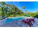 Inviting pool area surrounded by tropical greenery, featuring comfortable lounge chairs and a stylish hammock at 405 Magellan Dr, Sarasota, FL 34243