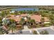 Aerial view of the clubhouse featuring its red tile roof, lush landscaping, palm trees, and a beautiful lake at 4719 Cabreo Ct, Bradenton, FL 34211