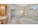 Bright bathroom featuring a large soaking tub and tiled shower with glass door, plus wood cabinets at 6961 Scrub Jay Dr, Sarasota, FL 34241