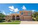 Beautiful two-story stucco home with a tile roof, arched entryway, and lush landscaping under a bright, partly cloudy sky at 6961 Scrub Jay Dr, Sarasota, FL 34241