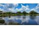 Picturesque view of a serene pond, reflecting the blue sky and clouds, with homes and greenery lining the shore at 6961 Scrub Jay Dr, Sarasota, FL 34241