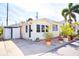 Charming yellow home featuring an open carport, tropical plants, and an inviting brick patio at 7 High St, Bradenton, FL 34208