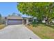 Charming single-story home featuring a well-maintained lawn, mature trees, and a dark gray garage door at 7104 13Th E St, Sarasota, FL 34243