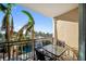 Outdoor patio with black metal railings, two chairs, and a table overlooking palm trees and water fountain at 750 N Tamiami Trl # 407, Sarasota, FL 34236