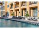 Exterior view of the pool deck area featuring lounge chairs, potted palm trees, and a clear blue pool at 750 N Tamiami Trl # 407, Sarasota, FL 34236