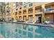 Exterior daytime view of the pool area features clear water, building with balconies, and lounge chairs at 750 N Tamiami Trl # 407, Sarasota, FL 34236