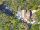 Aerial view of a home with screened-in pool with views of a small body of water and lush greenery at 7717 27Th W Ave, Bradenton, FL 34209