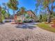 Exterior elevation of a two-story home with a brick driveway, second story deck and lush tropical landscaping at 7717 27Th W Ave, Bradenton, FL 34209
