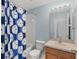 Bathroom with blue shower curtain, toilet, and sink with a wooden cabinet at 8850 Christie Dr, Largo, FL 33771