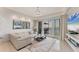 Bright living room with a cozy sofa, decorative mirror, balcony access, and views of the lake at 10520 Boardwalk Loop # 504, Lakewood Ranch, FL 34202
