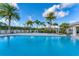 Beautiful community pool with lounge chairs and tropical palm trees under a bright sky at 10520 Boardwalk Loop # 504, Lakewood Ranch, FL 34202